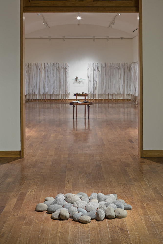 A pile of rocks in a room sits in front of a long shot of 3 other rock displays